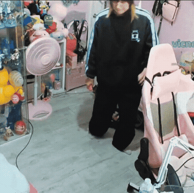 A Person Standing In A Room With A Pink Chair And A Sign That Says Vichu GIF