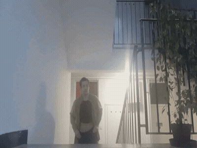 A Person Standing In Front Of A Balcony With A Plant GIF