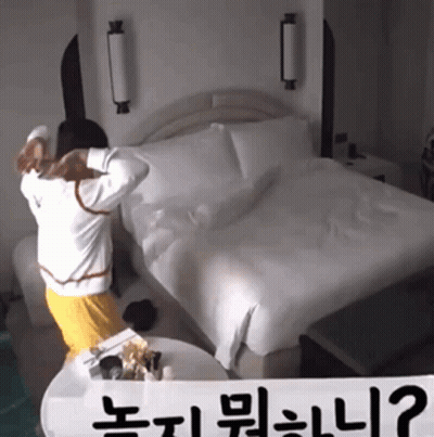 A Person Standing In Front Of A Bed With A Sign That Says " ? " GIF