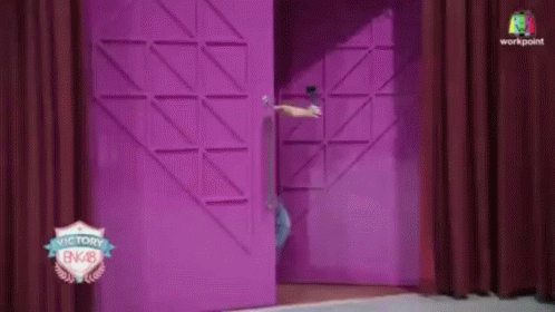 A Person Standing In Front Of A Pink Door That Says Victory Bnk28 GIF
