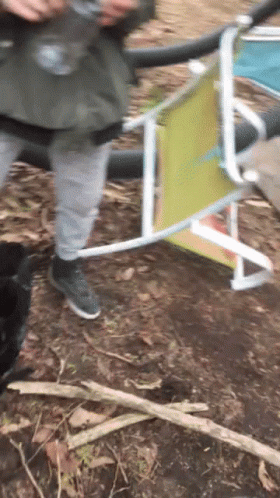 A Person Standing Next To A Folding Chair That Has A Yellow Back GIF