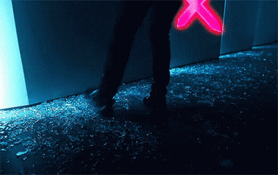 A Person Standing On A Broken Glass Floor With A Neon Sign In The Background . GIF