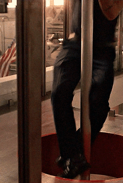 A Person Standing On A Pole In Front Of A Window With An American Flag In The Background GIF