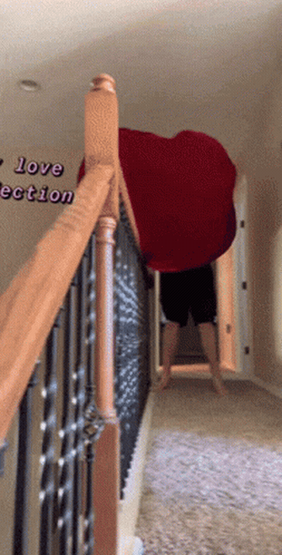 A Person Standing On A Set Of Stairs Holding A Large Red Heart Shaped Blanket GIF