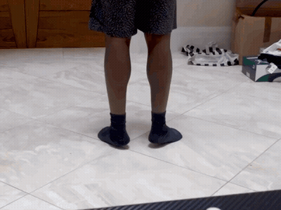A Person Standing On A Tiled Floor Wearing A Pair Of Socks GIF