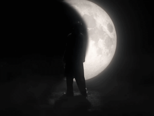 A Person Stands In Front Of A Full Moon GIF