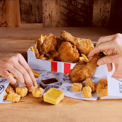 A Person Taking A Piece Of Fried Chicken Out Of A Box That Says Kfc GIF