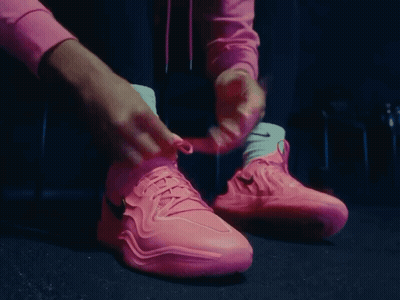 A Person Tying Their Pink Nike Shoes With White Socks GIF