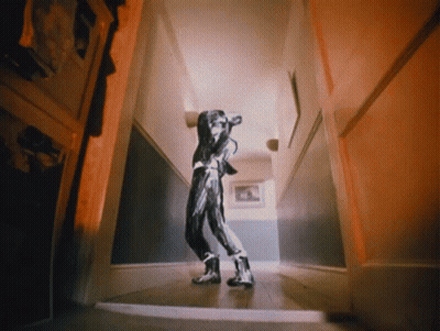 A Person Walking Down A Hallway With A Picture On The Wall GIF
