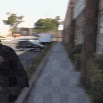 A Person Walking Down A Sidewalk With A Bag On Their Back GIF