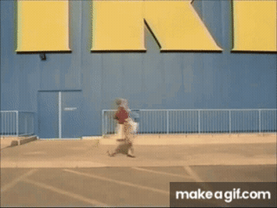 A Person Walking In Front Of A Large Yellow Sign That Says Ikea GIF