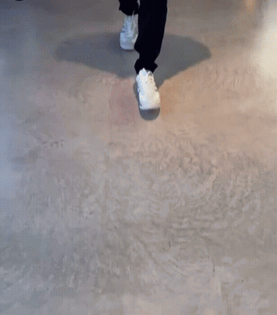 A Person Walking On A Concrete Floor Wearing White Shoes GIF