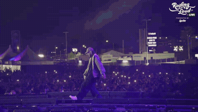 A Person Walking On A Stage With A Rolling Loud Logo In The Background GIF