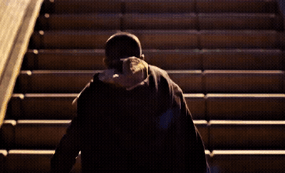 A Person Walking Up A Set Of Stairs Wearing A Black Hat GIF