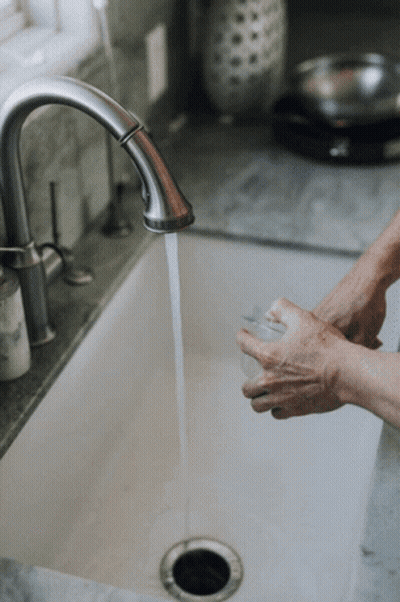 A Person Washing Their Hands In A Sink With Water Running GIF