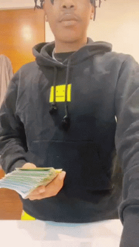 A Person Wearing A Black Hoodie With A Yellow Smiley Face On The Front GIF