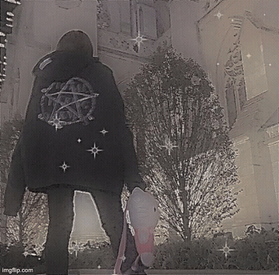 A Person Wearing A Black Jacket With A Pentagram On The Back Is Standing In Front Of A Building . GIF
