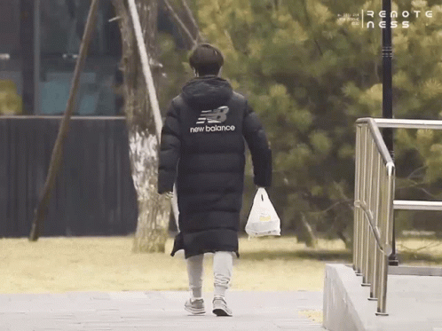A Person Wearing A Black New Balance Jacket Is Walking Down A Sidewalk GIF