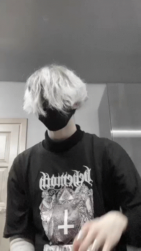 A Person Wearing A Black Shirt With A Cross On It And A Black Mask GIF