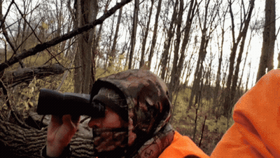 A Person Wearing A Camo Hooded Jacket Looking Through Binoculars GIF