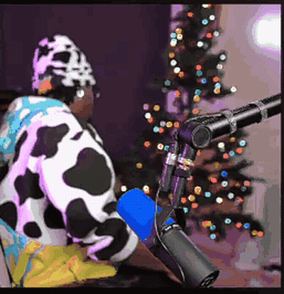 A Person Wearing A Cow Costume Is Sitting In Front Of A Microphone . GIF