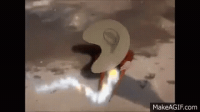 A Person Wearing A Cowboy Hat Is Standing On A Beach With A Flame Coming Out Of It . GIF