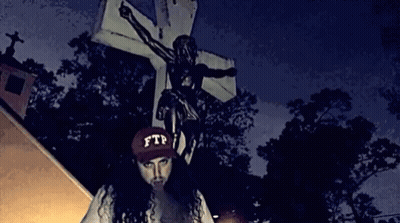 A Person Wearing A Ftp Hat Stands In Front Of A Cross GIF