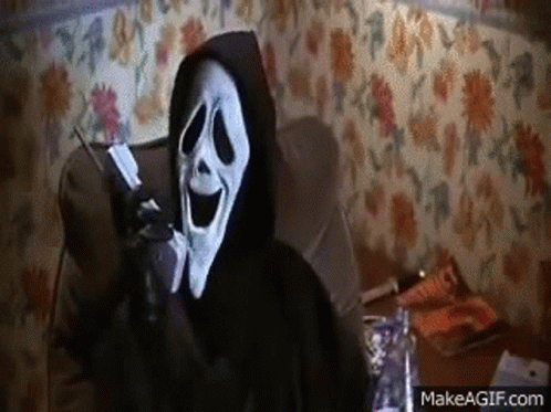 A Person Wearing A Ghostface Mask Is Sitting In A Chair Talking On A Cell Phone . GIF