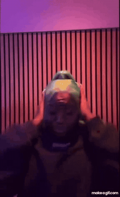 a person wearing a green hat is standing in front of a purple and red wall .