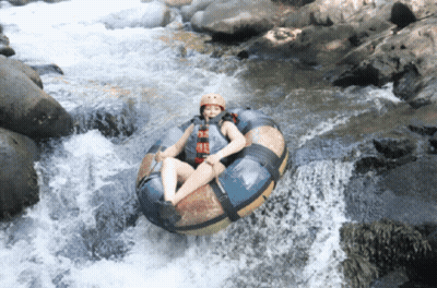 A Person Wearing A Helmet Is Floating Down A River On A Tube GIF