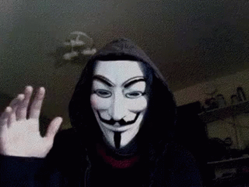 A Person Wearing A Hooded Jacket And A Anonymous Mask Is Waving GIF