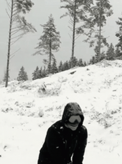 A Person Wearing A Hooded Jacket Is Standing In The Snow GIF