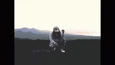 A Person Wearing A Hoodie And A Hat Is Sitting In The Middle Of A Field GIF