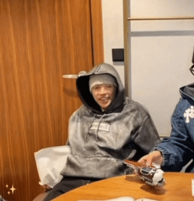 A Person Wearing A Hoodie That Says Supreme On It Sits At A Table GIF