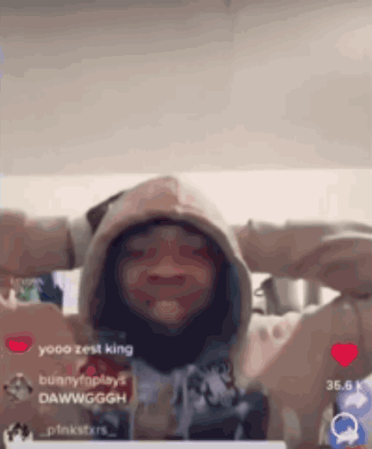 A Person Wearing A Hoodie With Their Hands Behind Their Head Is Making A Funny Face . GIF