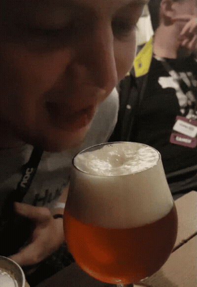A Person Wearing A Lanyard That Says ' Snc ' On It Looks At A Glass Of Beer GIF