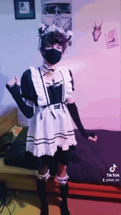 A Person Wearing A Maid Costume And A Mask Is Standing In A Room . GIF