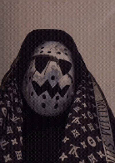 A Person Wearing A Mask And A Louis Vuitton Scarf Around Their Neck GIF