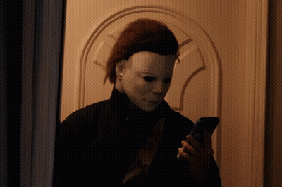 A Person Wearing A Mask Is Looking At Their Phone GIF