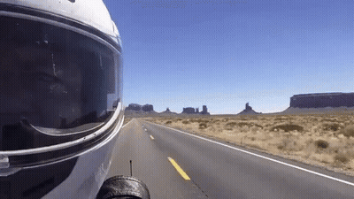 A Person Wearing A Motorcycle Helmet Is Driving Down A Desert Road GIF