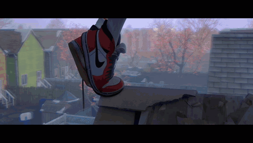 A Person Wearing A Pair Of Red And White Nike Shoes Is Standing On A Ledge GIF