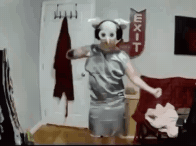 A Person Wearing A Pig Mask And Headphones Is Dancing In A Living Room . GIF
