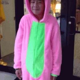 A Person Wearing A Pink And Green Costume Is Standing In Front Of A Door GIF