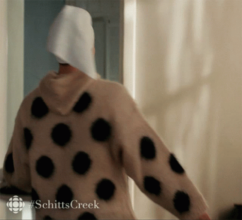 A Person Wearing A Polka Dot Sweater With #Schitts Creek Written On It GIF