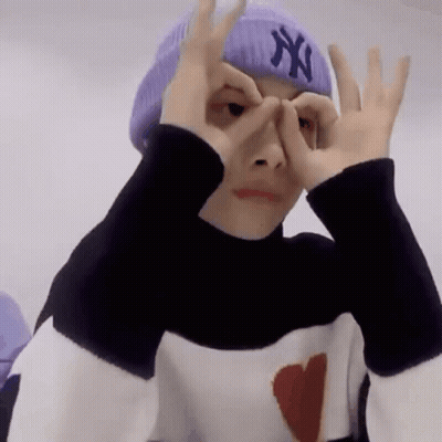 A Person Wearing A Purple Hat And A Black And White Sweater Is Making A Funny Face . GIF