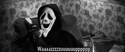 A Person Wearing A Scream Mask Is Talking On A Cell Phone While Sitting On A Couch . GIF