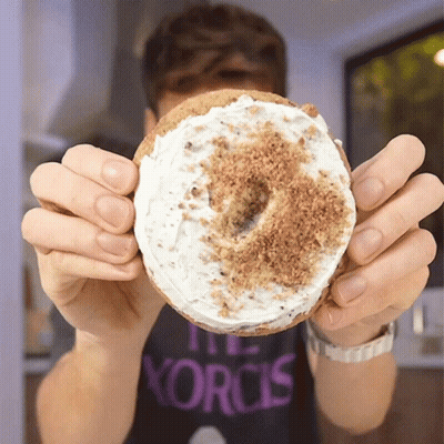 A Person Wearing A Shirt That Says The Korcis Holds A Donut GIF