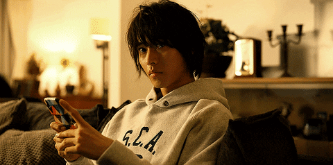 A Person Wearing A Sweatshirt That Says G.c.a. Looks At Their Phone GIF