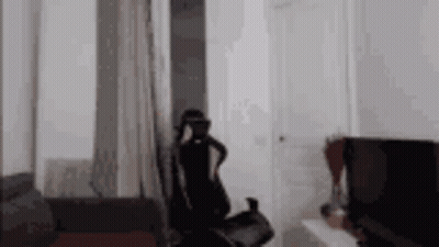 A Person Wearing A Virtual Reality Headset Is Sitting In A Living Room . GIF