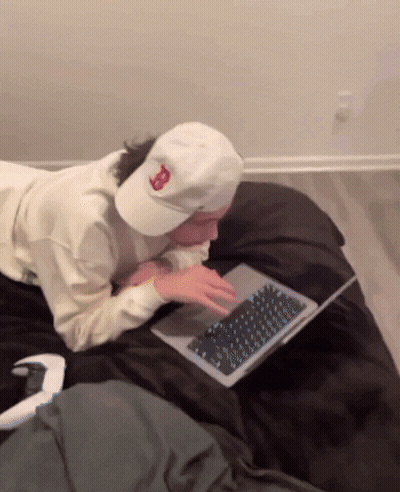 A Person Wearing A White Hat With The Letter B On It Is Using A Laptop GIF